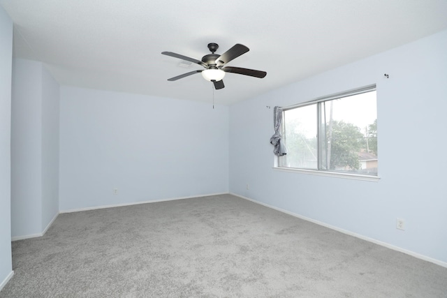 carpeted spare room with baseboards and a ceiling fan