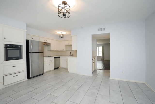 kitchen with stainless steel appliances, under cabinet range hood, baseboards, visible vents, and light countertops