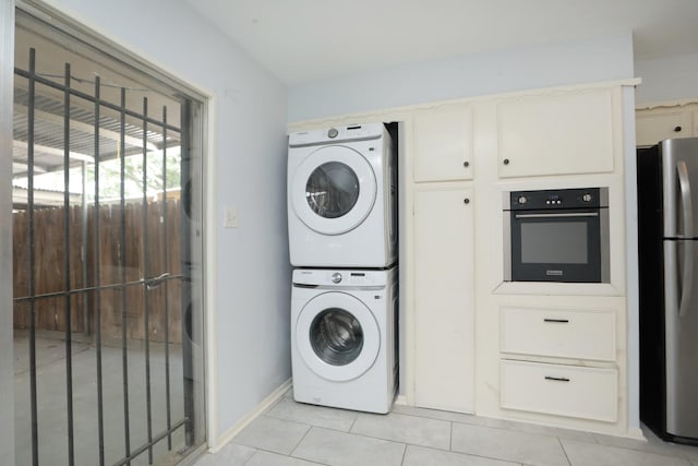 laundry area featuring laundry area, stacked washer / dryer, baseboards, and light tile patterned floors