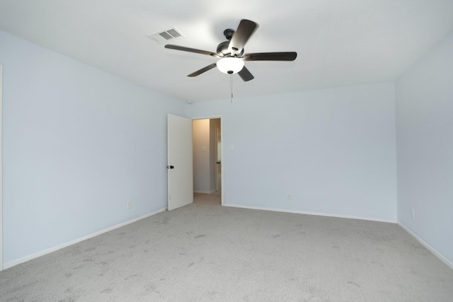 empty room with light colored carpet, baseboards, a ceiling fan, and visible vents
