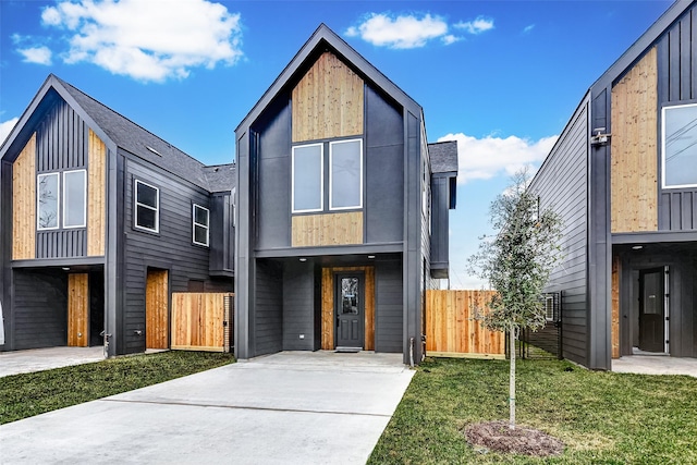 contemporary home featuring a gate, fence, a shingled roof, a front yard, and driveway