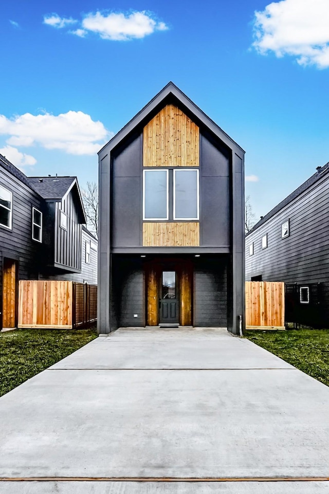 contemporary house with fence, an attached garage, and driveway