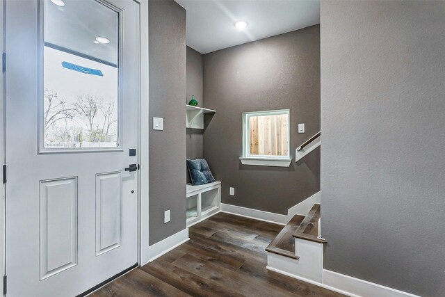 foyer entrance with baseboards, dark wood-style flooring, and stairway