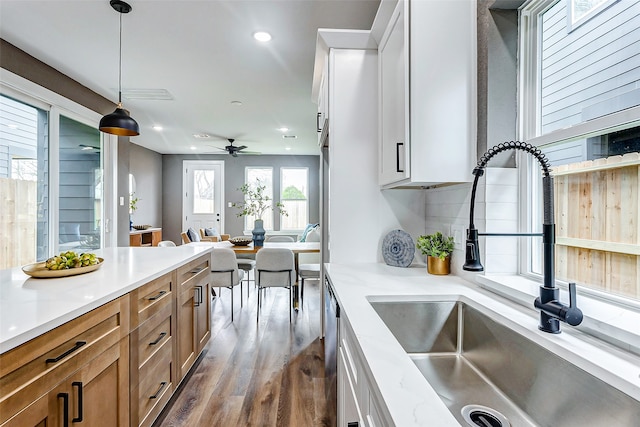 kitchen with brown cabinetry, dark wood finished floors, ceiling fan, a sink, and white cabinets