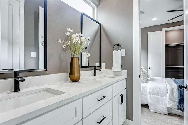 ensuite bathroom with a sink, double vanity, connected bathroom, and visible vents