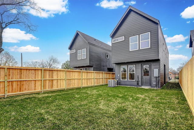 back of house with a yard, a fenced backyard, and central AC