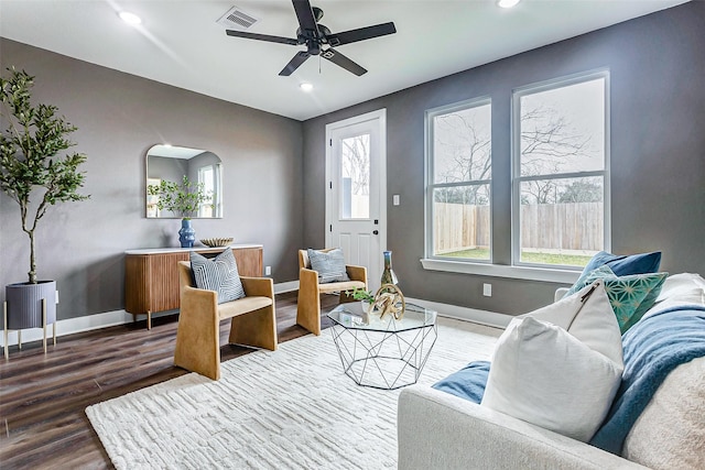 living area with baseboards, visible vents, dark wood-style flooring, and a ceiling fan