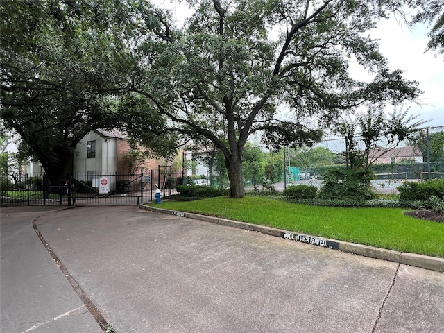 view of asphalt street featuring a gate, curbs, a gated entry, and traffic signs