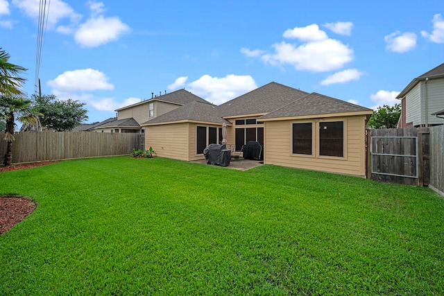 back of property featuring a lawn, a patio area, roof with shingles, and a fenced backyard