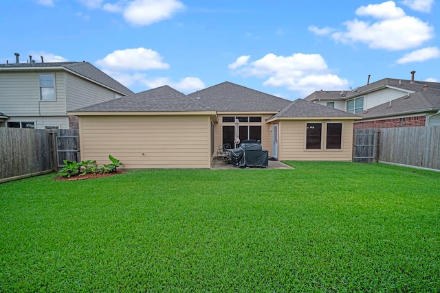 rear view of house with a yard, a fenced backyard, and a shingled roof