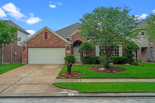 traditional-style house with an attached garage, concrete driveway, brick siding, and a front lawn