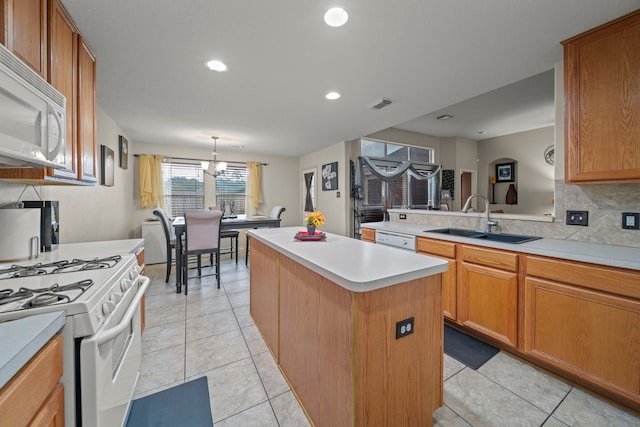 kitchen with a sink, visible vents, white appliances, light countertops, and a kitchen island