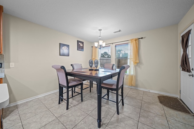 dining space featuring a textured ceiling, a notable chandelier, baseboards, and visible vents