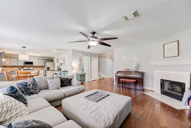 living room with a ceiling fan, baseboards, visible vents, stairs, and wood finished floors