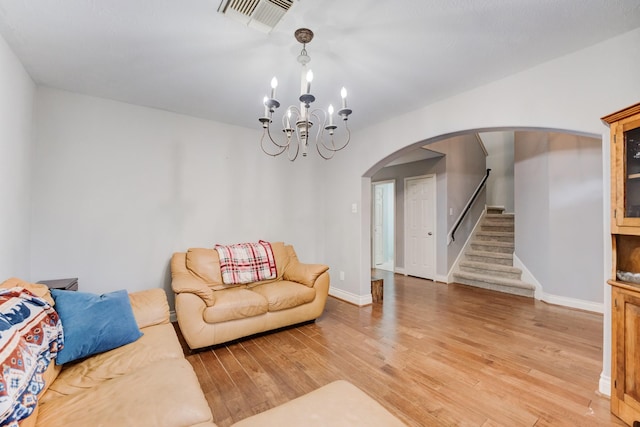 living area with light wood-type flooring, visible vents, stairway, arched walkways, and baseboards