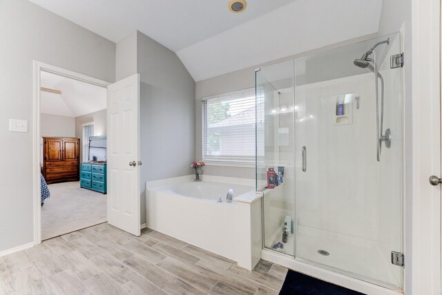 bathroom featuring a garden tub, wood finished floors, a shower stall, ensuite bath, and vaulted ceiling