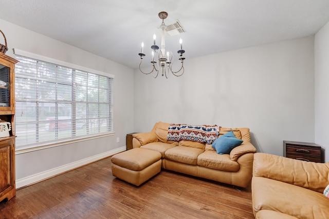 living room featuring wood finished floors, visible vents, baseboards, and a notable chandelier