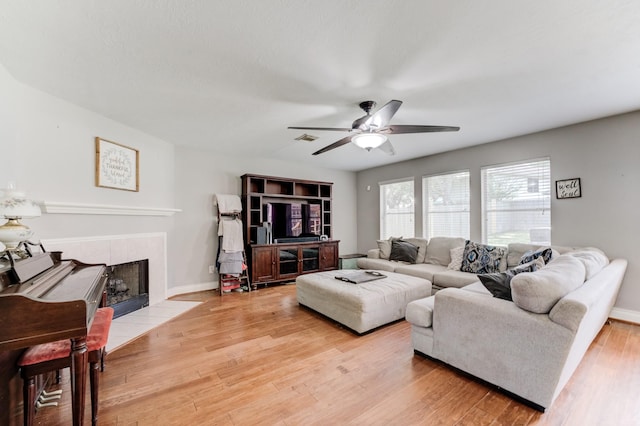 living room with wood finished floors, visible vents, a ceiling fan, baseboards, and a tile fireplace