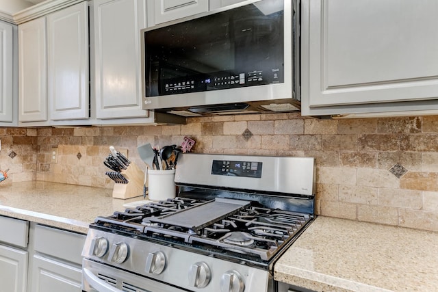 kitchen with tasteful backsplash, appliances with stainless steel finishes, and white cabinets