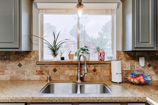 kitchen with tasteful backsplash, gray cabinetry, and a sink