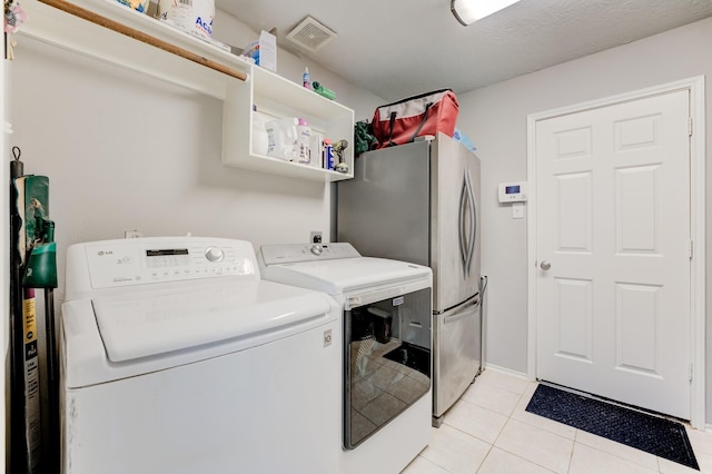 laundry area featuring washing machine and clothes dryer, laundry area, visible vents, and light tile patterned flooring