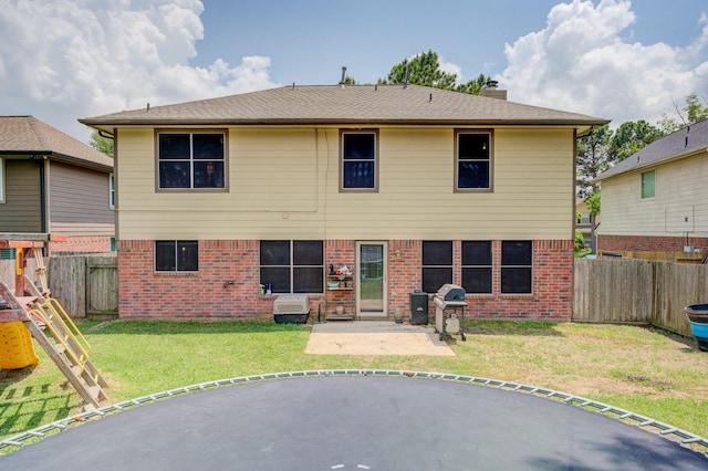 rear view of property with a chimney, a yard, brick siding, a patio area, and a fenced backyard