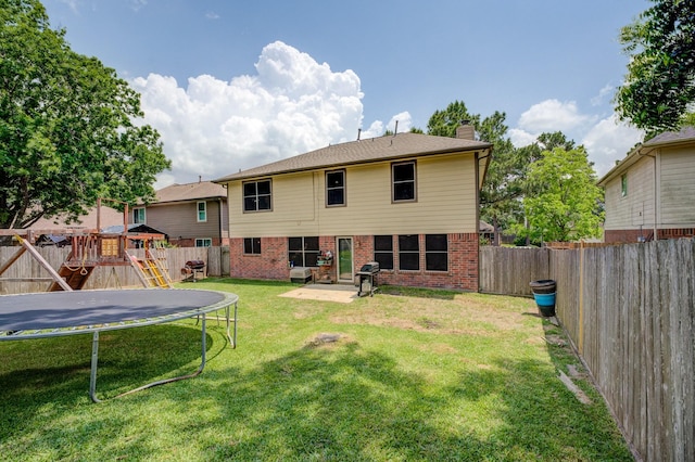 back of house with a trampoline, brick siding, a chimney, and a fenced backyard