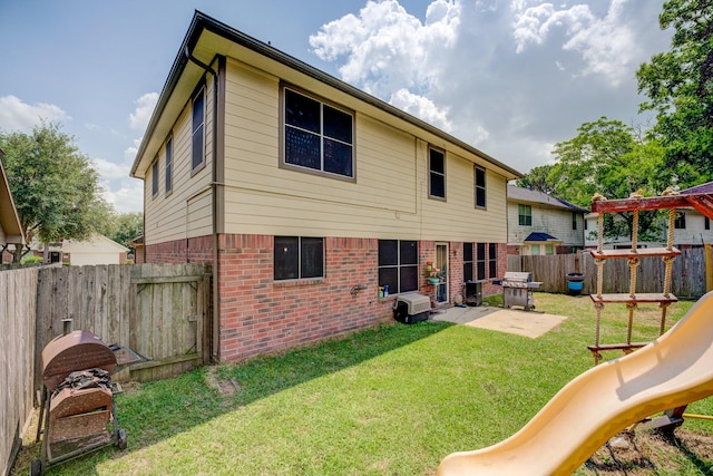 rear view of property with a yard, brick siding, a patio, a playground, and a fenced backyard
