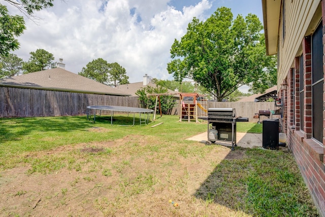 view of yard with a fenced backyard, a trampoline, a patio, and a playground