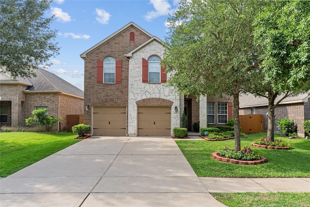 traditional home with fence, stone siding, driveway, a garage, and a front yard