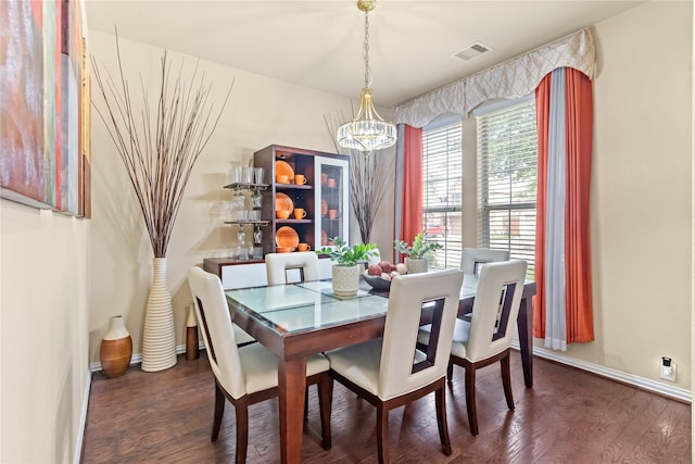 dining room featuring visible vents, wood finished floors, baseboards, and a notable chandelier