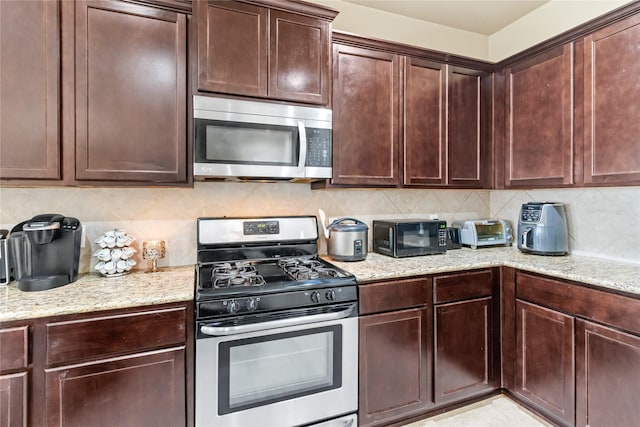kitchen with stainless steel appliances, decorative backsplash, and light stone counters