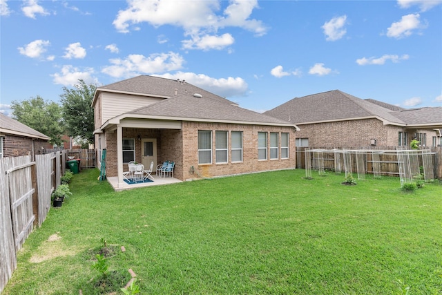rear view of property featuring a patio, a lawn, a fenced backyard, brick siding, and roof with shingles