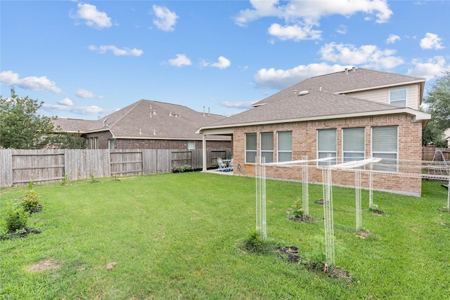 back of property featuring a fenced backyard, roof with shingles, brick siding, and a lawn