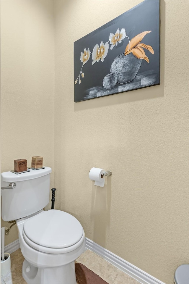 bathroom with toilet, baseboards, and tile patterned floors