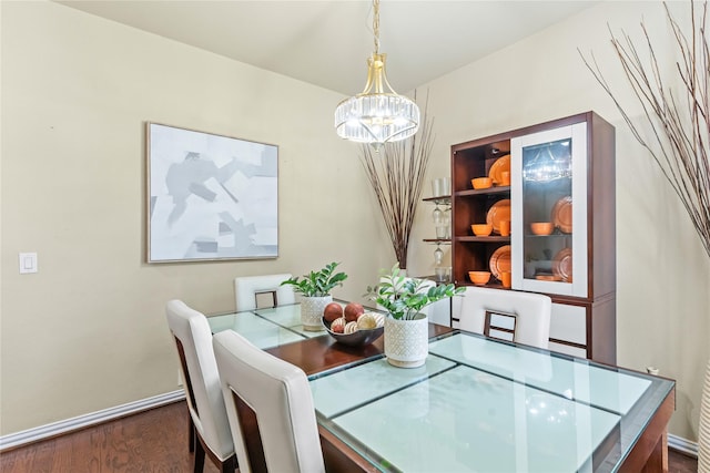 dining area with baseboards, a notable chandelier, and wood finished floors