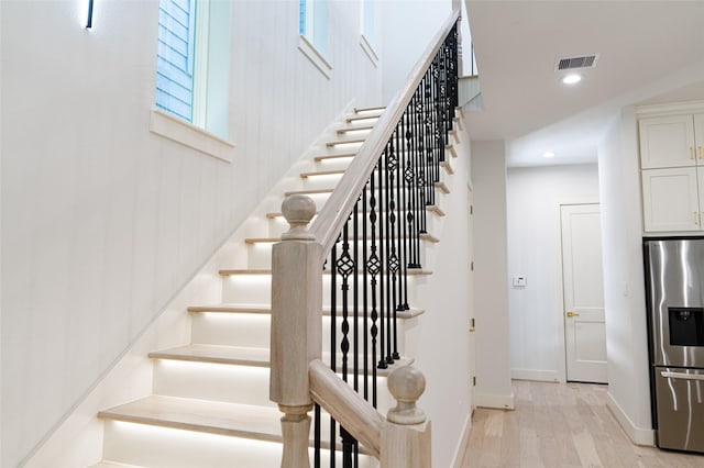 stairs with wood finished floors, recessed lighting, and baseboards