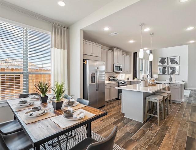 kitchen featuring stainless steel appliances, a kitchen island, light countertops, and dark wood finished floors