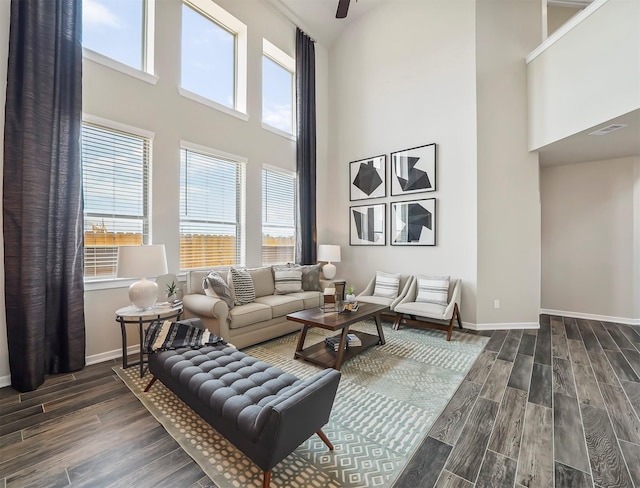 living area with baseboards, dark wood-style floors, and a high ceiling