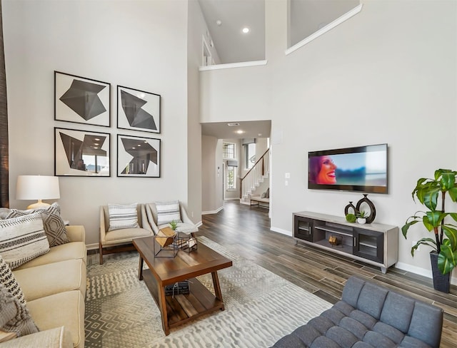 living room with recessed lighting, baseboards, stairs, wood finished floors, and a high ceiling