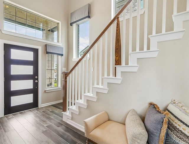 foyer entrance with stairway, wood finished floors, baseboards, and a healthy amount of sunlight
