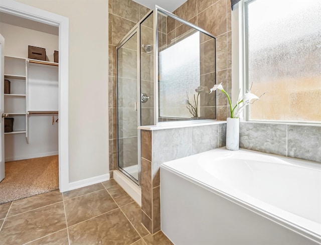 bathroom with baseboards, a shower stall, a garden tub, tile patterned floors, and a spacious closet