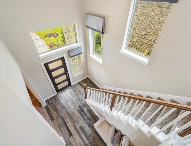 entrance foyer featuring stairway, a towering ceiling, baseboards, and wood finished floors
