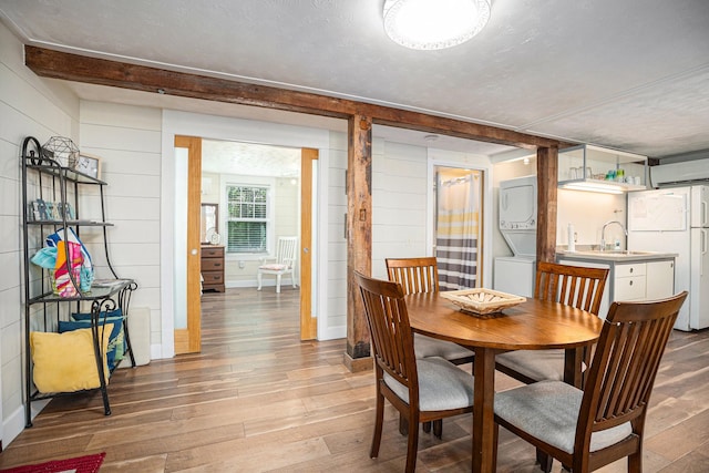 dining space with light wood-type flooring, stacked washer / dryer, and a textured ceiling