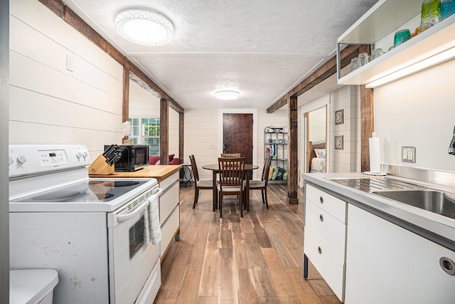 kitchen with light wood-style flooring, white cabinetry, white electric range oven, light countertops, and black microwave