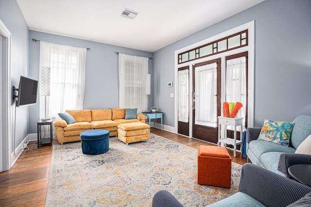 living area featuring french doors, wood finished floors, visible vents, and baseboards