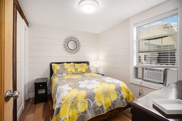 bedroom with cooling unit, wood walls, and wood finished floors