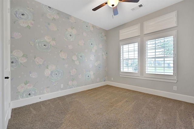 carpeted spare room with a ceiling fan, baseboards, and visible vents