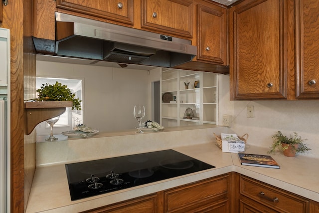 2002 Willowbend St, Conroe, TX 77301 - kitchen featuring under cabinet range hood, black electric stovetop, brown cabinetry, and light countertops
