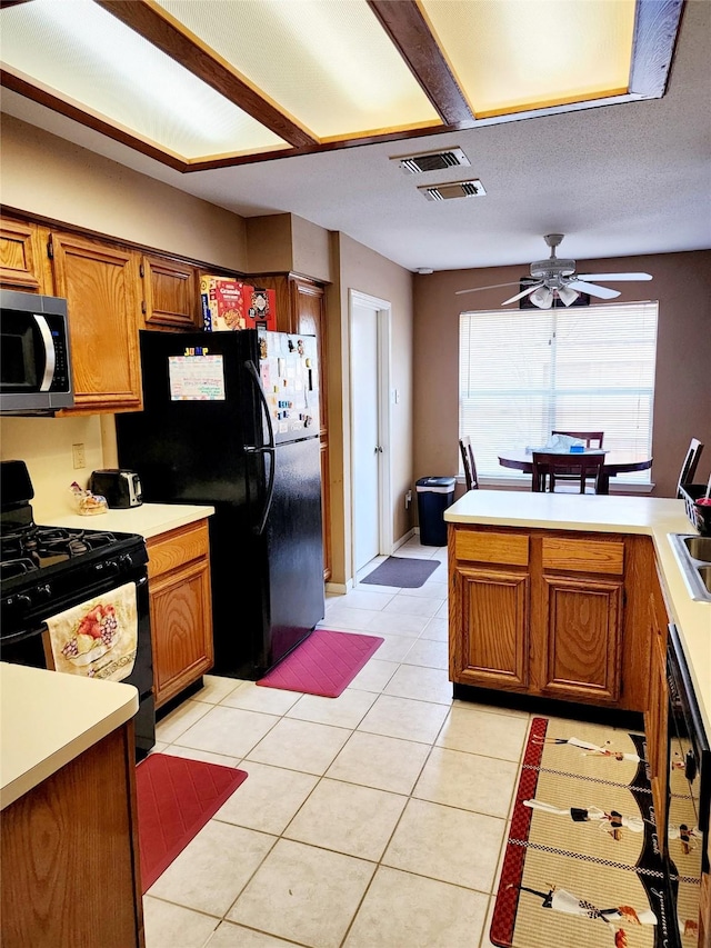 kitchen featuring ceiling fan, light countertops, black appliances, and brown cabinets